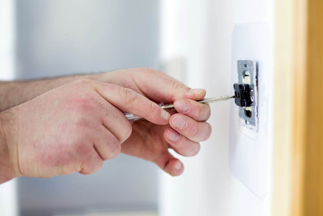 Electrician repairing a wall outlet